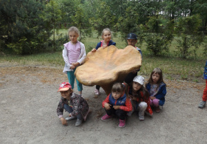 Dzieci stoją obok figury grzybka.